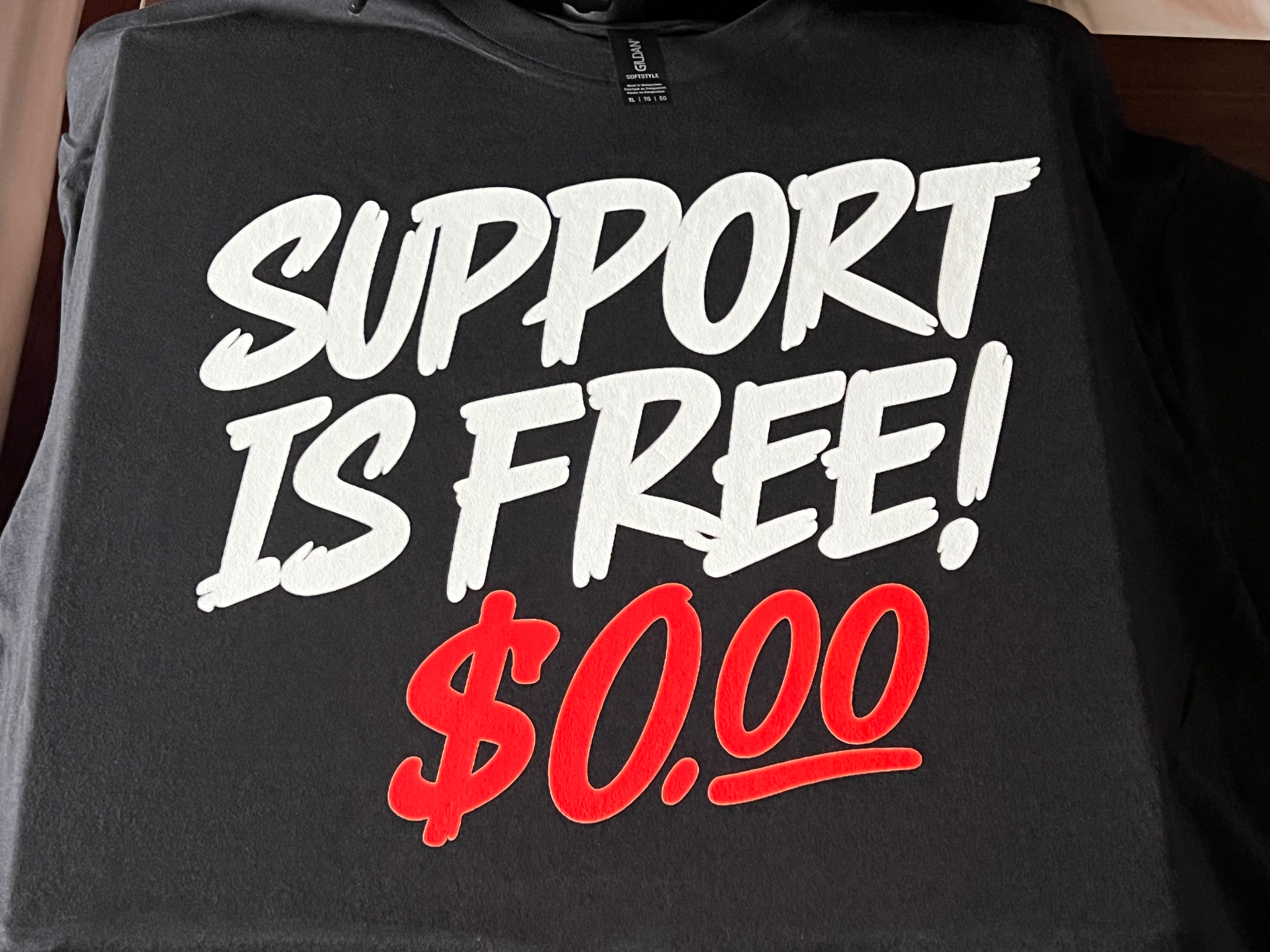 Black t-shirt with bold white and red lettering that reads Support Is Free $0.00